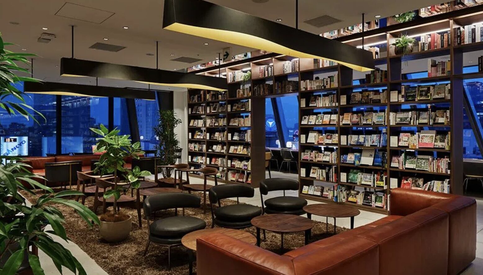 SHARE LOUNGE渋谷スクランブルスクエア店の本棚とフリー席のあるラウンジ内観