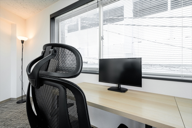 モニターと椅子が近接した狭いデスク環境の写真