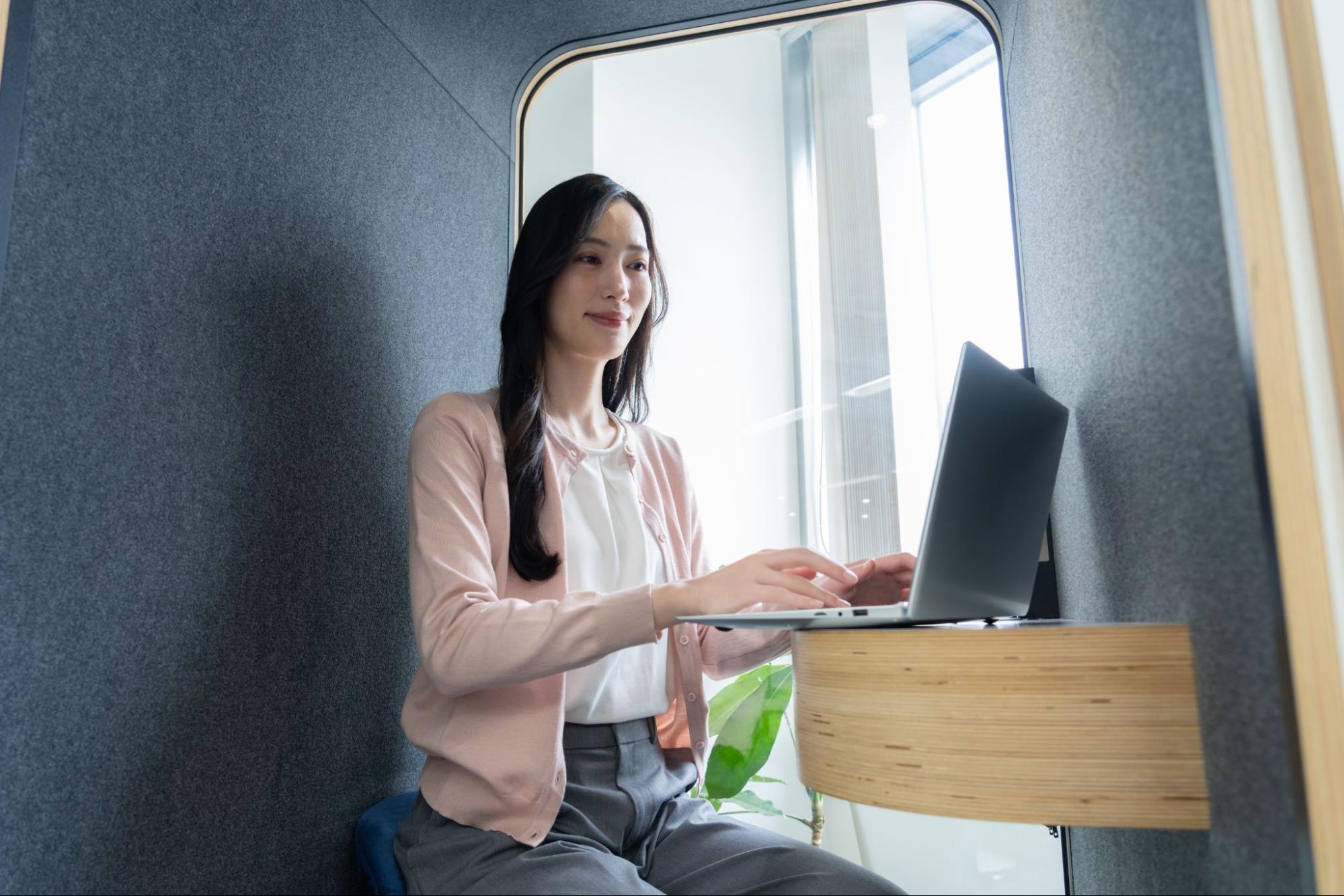 オフィス内に設置された1人用の集中ブースで作業をするビジネスマン