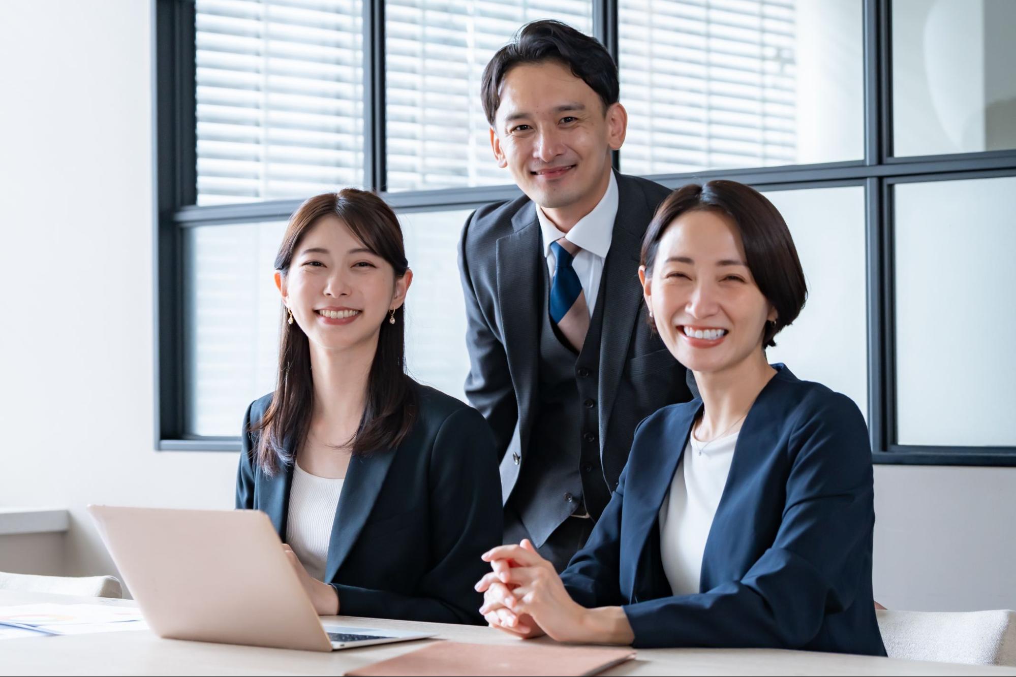 快適なオフィスでこちらに向かって微笑んでいる従業員3人